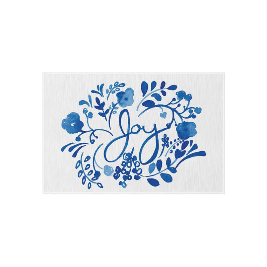 Vibrant blue floral watercolor outdoor rug with hand-lettered "Joy" text, soft chenille pile on porch patio